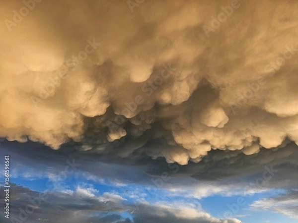 Obraz Storm clouds on sunset. Light in the dark and dramatic storm clouds. Background of storm clouds before a thunderstorm. Mammatus clouds