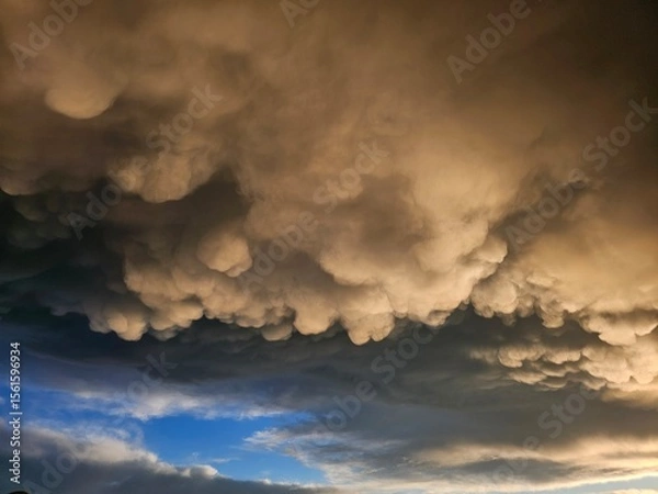 Obraz Storm clouds on sunset. Light in the dark and dramatic storm clouds. Background of storm clouds before a thunderstorm. Mammatus clouds