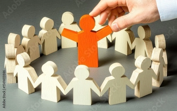 Fototapeta A single orange wooden figure stands in a circle of smaller white figures