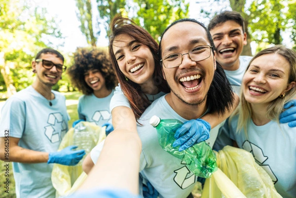 Fototapeta Group of volunteer cleaning picking up plastic litter in the park - Diverse group of people collect trash in the forest - Environmental protection, non profits organization and save the planet concept