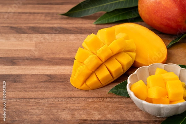 Fototapeta Fresh ripe mango with cubes on wooden table background.