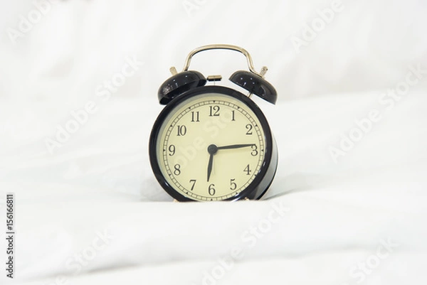 Fototapeta Alarm clock on bed in morning with sun light