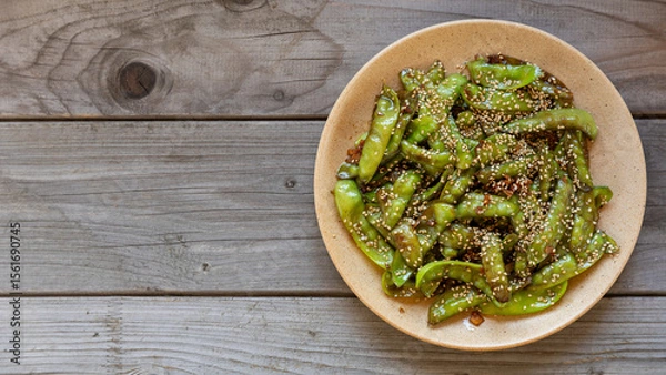 Obraz Asian Sugar Snap Peas. Pea pods stir-fried with garlic, ginger, and soy sauce, and sprinkled with toasted sesame seeds. Rustic wooden table with space for text.