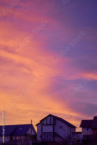 Fototapeta landscape with a reddish sky above some houses at sunset