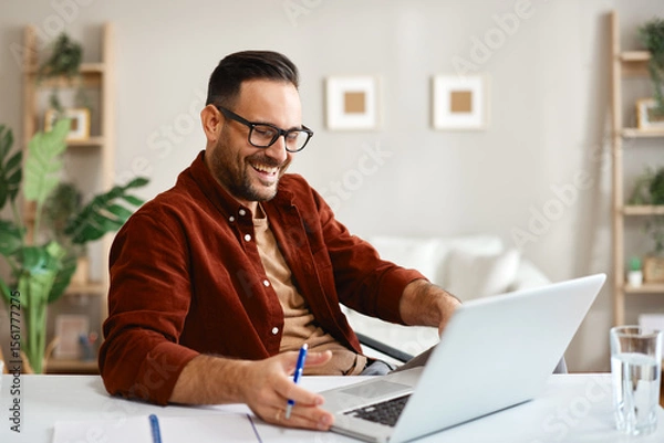 Obraz Freelancer smiling and working from home using laptop