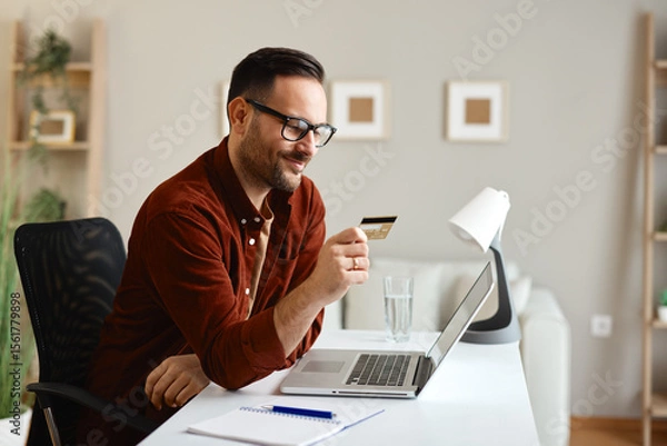 Obraz Freelancer smiling and making online payment with credit card at home