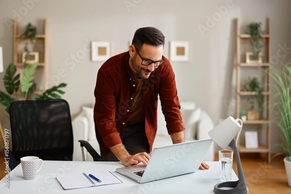 Obraz Freelancer working from home office standing at desk typing on laptop