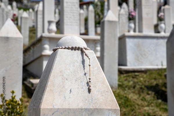 Fototapeta Rosary Beads Adorning a Marble Gravestone in a Peaceful Cemetery, Kovaci Cemetery in Sarajevo.