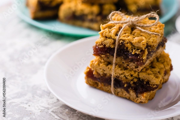 Obraz Delicious homemade pie with apple jam. Appetizing pieces of grated pie with jam on a white plate on a light table, many crispy pieces of pie on the background