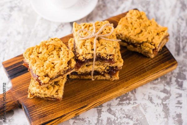 Obraz Delicious homemade pie with apple jam. Appetizing slices of grated pie with jam on a wooden board and coffee in a white cup on a light table.