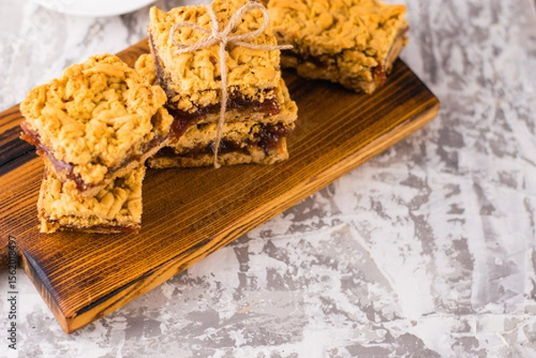 Obraz Delicious homemade pie with apple jam. Appetizing slices of grated pie with jam on a wooden board and coffee in a white cup on a light table.