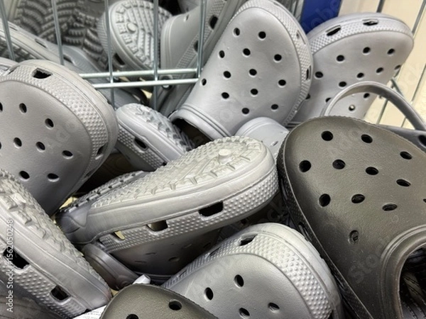 Obraz Pile of grey rubber clogs Crocs-style shoes in store basket. Comfortable casual footwear display for everyday use