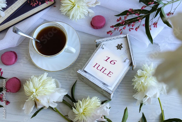 Fototapeta Calendar for June 16: number 16, name of the month June in English on a desk calendar among peonies, cups of tea and cupcakes