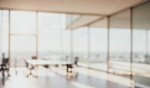 Fototapeta Blurred empty office room with large windows and a table with chairs.