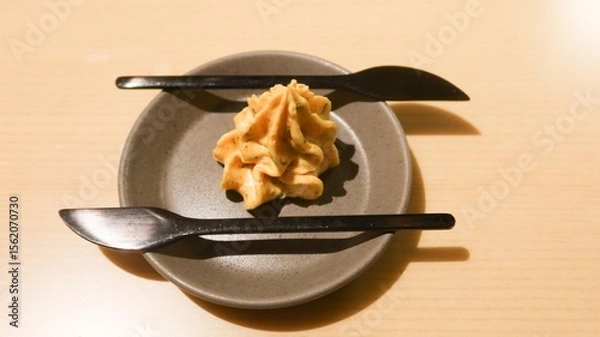 Fototapeta close up of a creamy golden colour spread or butter in swirl cream shape with two black knife on the side
