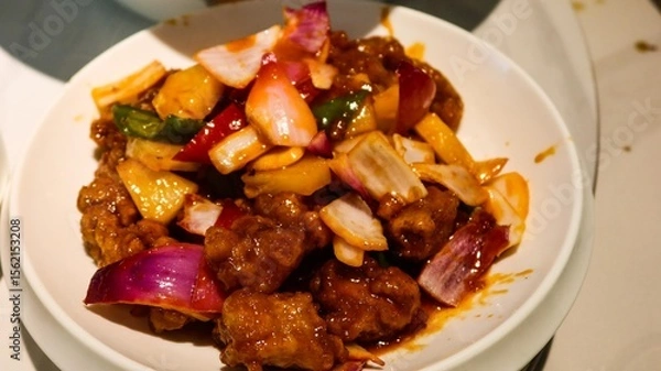 Fototapeta close up of a Cantonese dish- sweet and sour deep fried pork rib with onion, green and yellow pepper and pineapple on a white plate