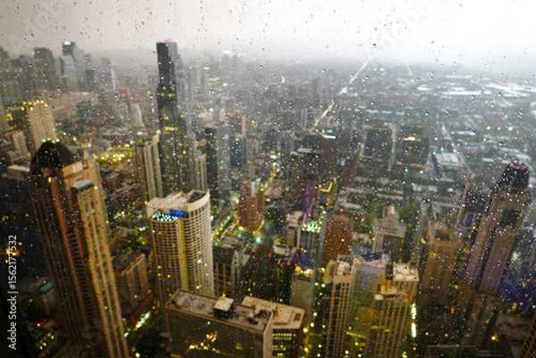 Fototapeta Highrise Buildings or Skyscrapers in Big City During Rainstorm with Rain Drops on Window