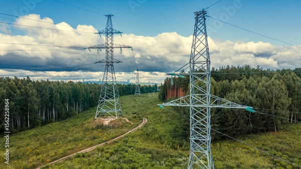 Obraz Power lines in a green field in the sunny summer day. Electrical substation. Drone view.