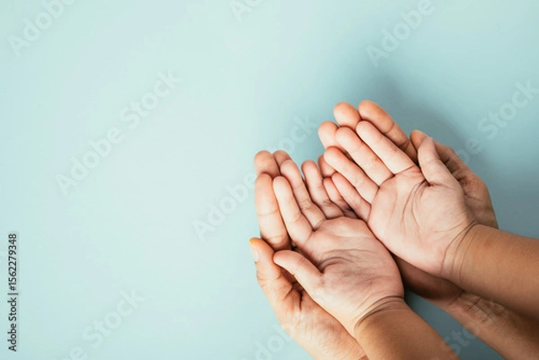 Fototapeta Family hands stack in close-up top view isolated background. Parents and child hold empty space together expressing support on Family and Parents Day.