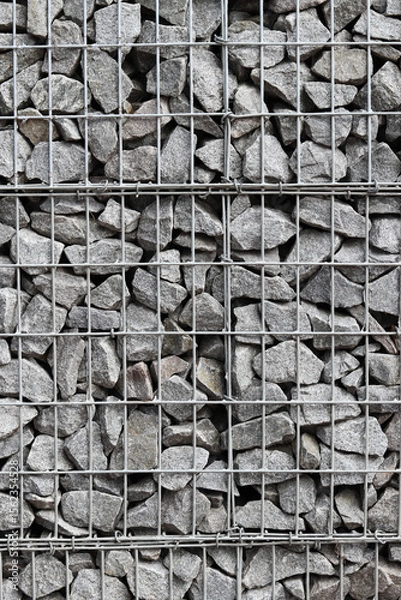 Fototapeta Rubble stone in galvanized mesh. Background. Gabion mattress made of woven mesh with stones for creating walls. Stones in mesh, creating decorative walls, strengthening