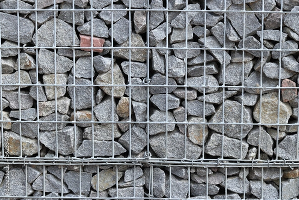 Fototapeta Rubble stone in galvanized mesh. Background. Gabion mattress made of woven mesh with stones for creating walls. Stones in mesh, creating decorative walls, strengthening
