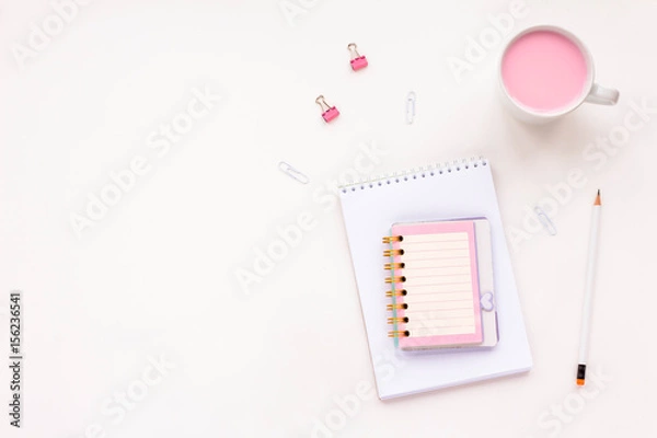 Obraz Woman's desk workspace with pink notebook, empty blank, pink yogurt, white pencil and clips on white background. Top view, flat lay, copy space.