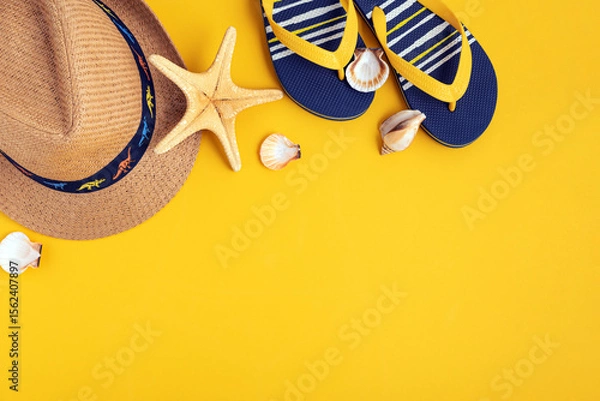 Obraz Kids beach summer frame from sea shells, straw hat, sandals on yellow background. Top view. Copy space