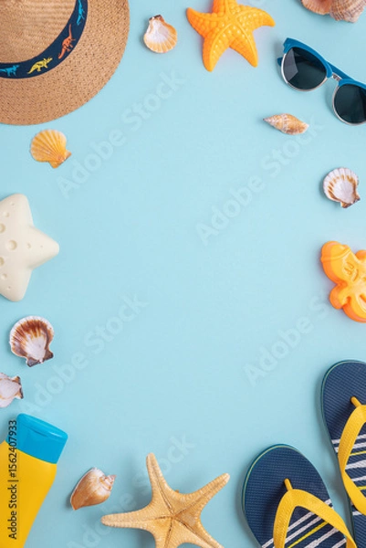 Obraz Colorful and playful summer frame from kids beach molds, straw hat, sandals and sunglasses on blue background. Top view. Copy space