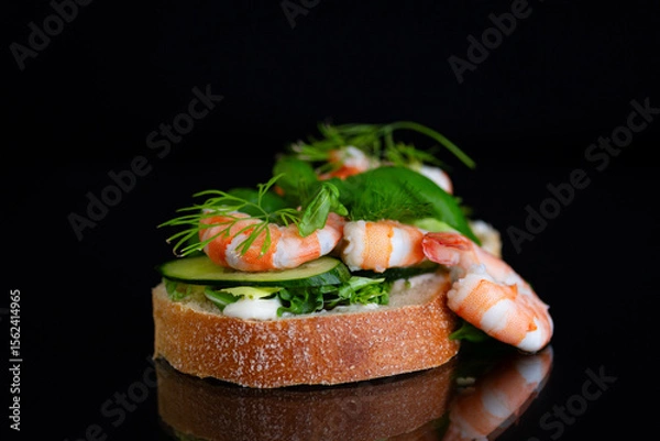 Obraz appetizing sandwich with salad and shrimps on a black background
