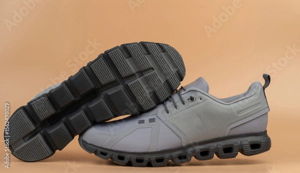 Obraz Stylish grey athletic shoes positioned on neutral background for modern look