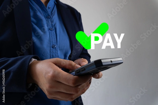 Fototapeta Businessman's hands holding a smartphone with a green check mark icon with the word "PAY." Authorized payment concept.