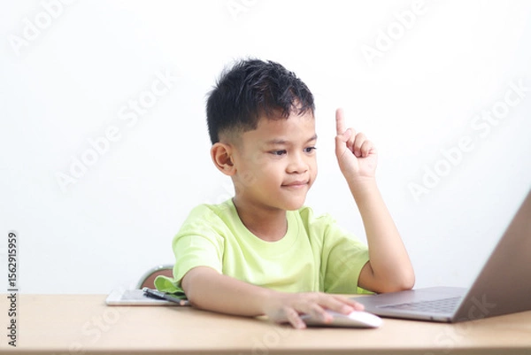 Fototapeta Young boy studying and doing homework at home with notebook and laptop. Concept of distance learning, education, homeschooling, and online classes for children.