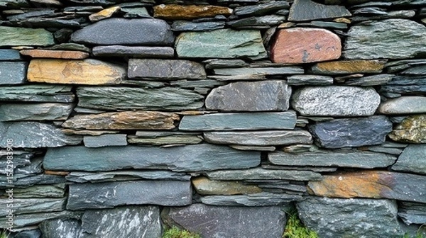 Fototapeta Varied slate rocks form a layered textured stone wall