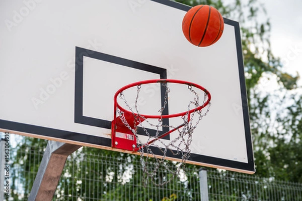 Obraz Street basketball action  ball flying toward hoop with metal chain net