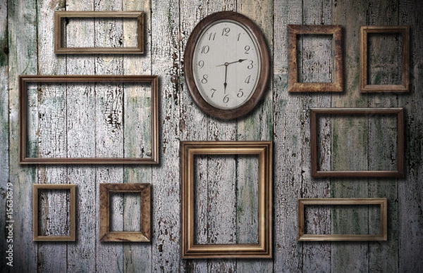 Fototapeta empty frames and watch on wooden wall