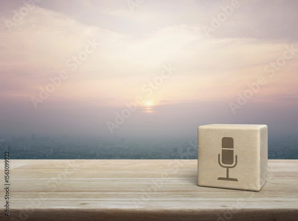 Fototapeta Microphone flat icon on wood block cube on wooden table over city tower and skyscraper at sunset, vintage style, Business communication concept