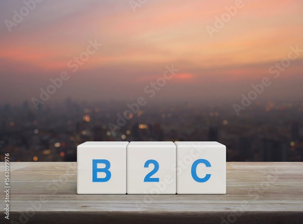 Fototapeta B2C acronym on white block cubes on wooden table over blur of cityscape on warm light sundown, Business to customer marketing and strategy concept