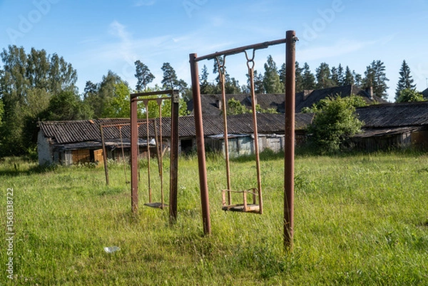 Fototapeta Rusty Swings in Abandoned Playground Overgrown with Grass. Forgotten Childhood — Rusty Playground in Overgrown Rural Field

.