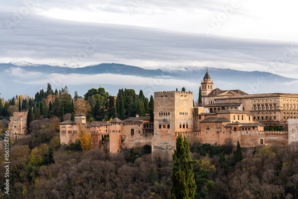 Fototapeta The Alhambra in Granada, Spain, with the Sierra Nevada mountains in the background at sunset. This historic site is a key tourist destination in Andalusia.