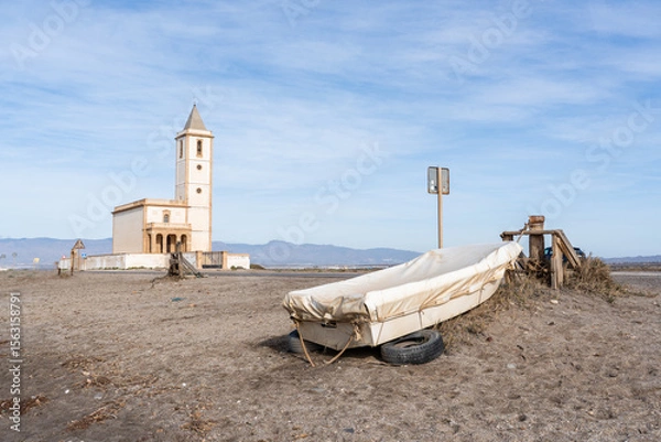 Fototapeta The Ermita de la Virgen del Mar with a covered boat in a minimalist setting under a sunny sky. Located in Almeria near the Cabo de Gata National Park.