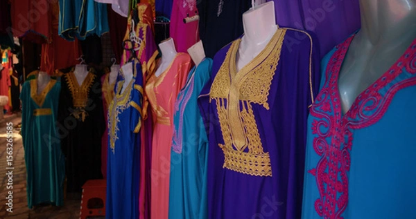 Fototapeta Stall selling colorful traditional clothing with fine embroidery in the old town of Sousse. Street market with clothes specific to Tunisia.