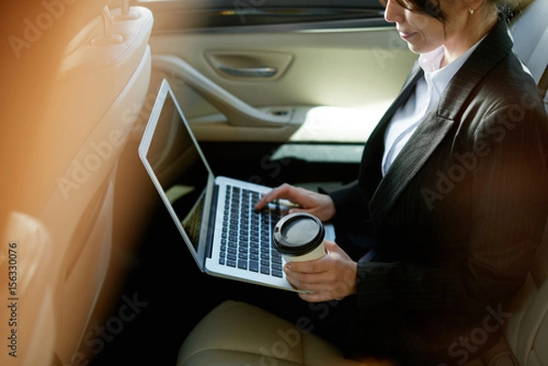 Obraz Smiling businesswoman in a car with coffee