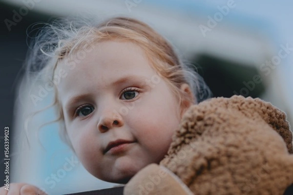 Fototapeta Beautiful 3-year-old girl playing on a neighborhood playground swinging, running on the grass, and enjoying fresh air. A joyful, natural moment full of real emotions and unaltered beauty