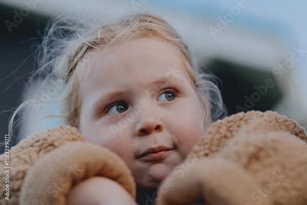 Fototapeta Beautiful 3-year-old girl playing on a neighborhood playground swinging, running on the grass, and enjoying fresh air. A joyful, natural moment full of real emotions and unaltered beauty