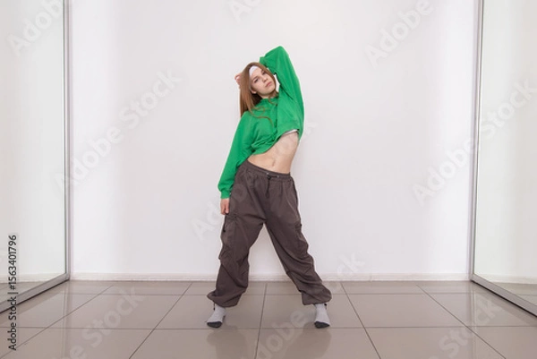 Obraz Dancer showcases movements in green outfit during studio practice session in bright space