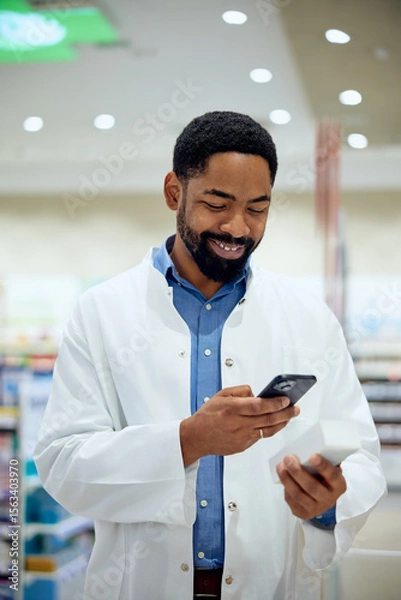 Fototapeta Pharmacist Using Smartphone While Smiling in Modern Pharmacy Store