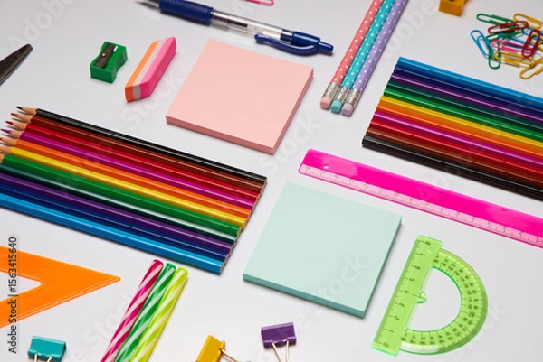 Fototapeta Brightly colored stationery supplies including pencils, sticky notes, rulers, and clips are organized on a workspace, ideal for school projects or office tasks