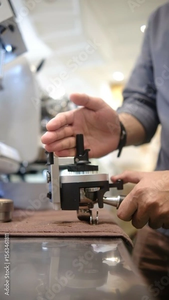 Fototapeta person barista using modern grinder machine to prepare coffee grounds in cafe features digital display and  polished metal finish.  