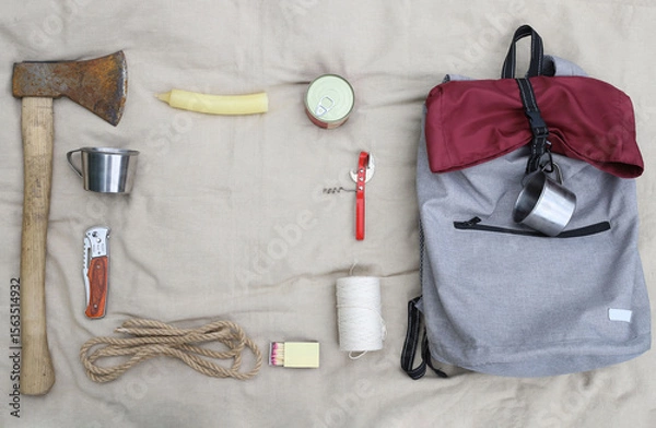 Obraz Hiking. Things and objects for tourism and survival in the forest or mountains. There is an axe, matches, canned food, rope, knife, backpack, headlamp, mugs