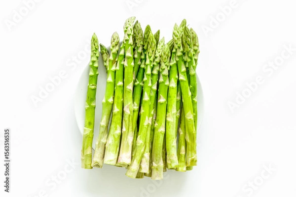 Obraz Fresh asparagus on plate on white background top-down copy space
